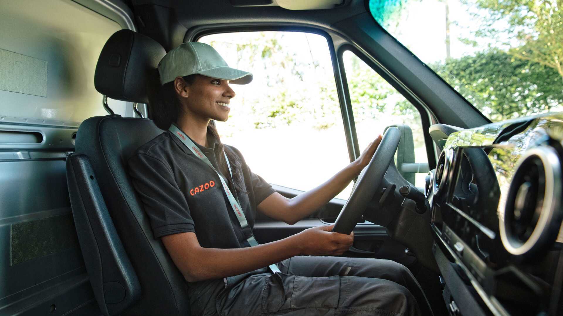 Un livreur spécialisé dans un camion Cazoo livrant une voiture à un client