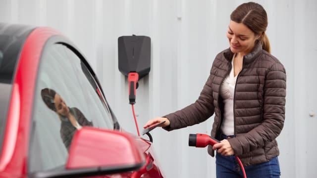 Woman charging a Tesla Model 3 electric car